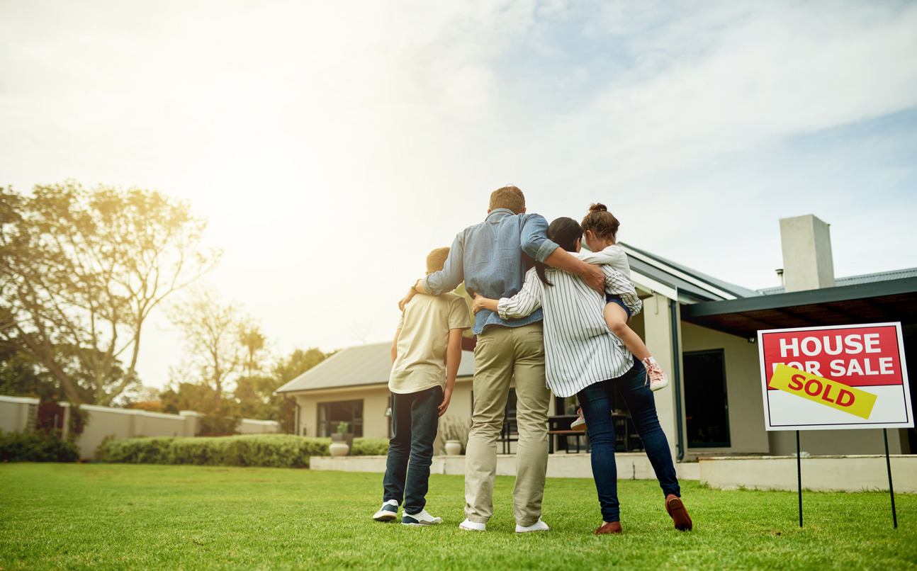 Family hugging in front of house for sale that sold