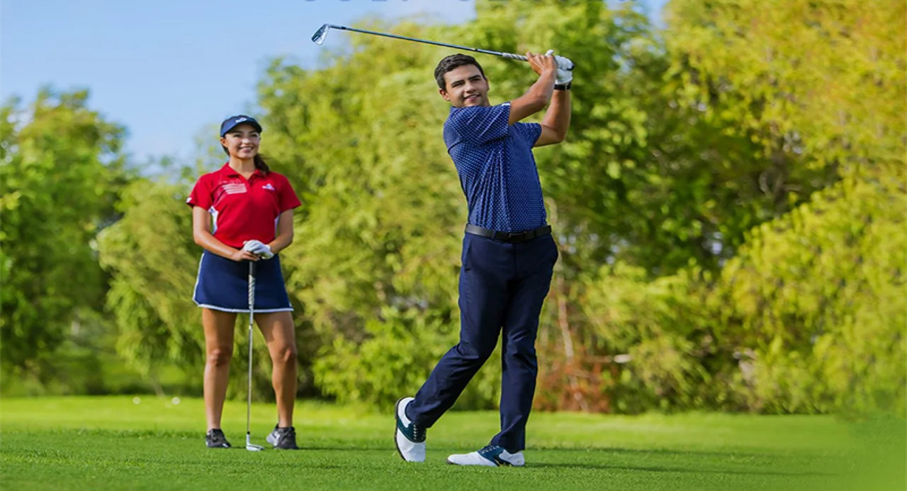 man swinging golf club and woman standing behind him holding golf club
